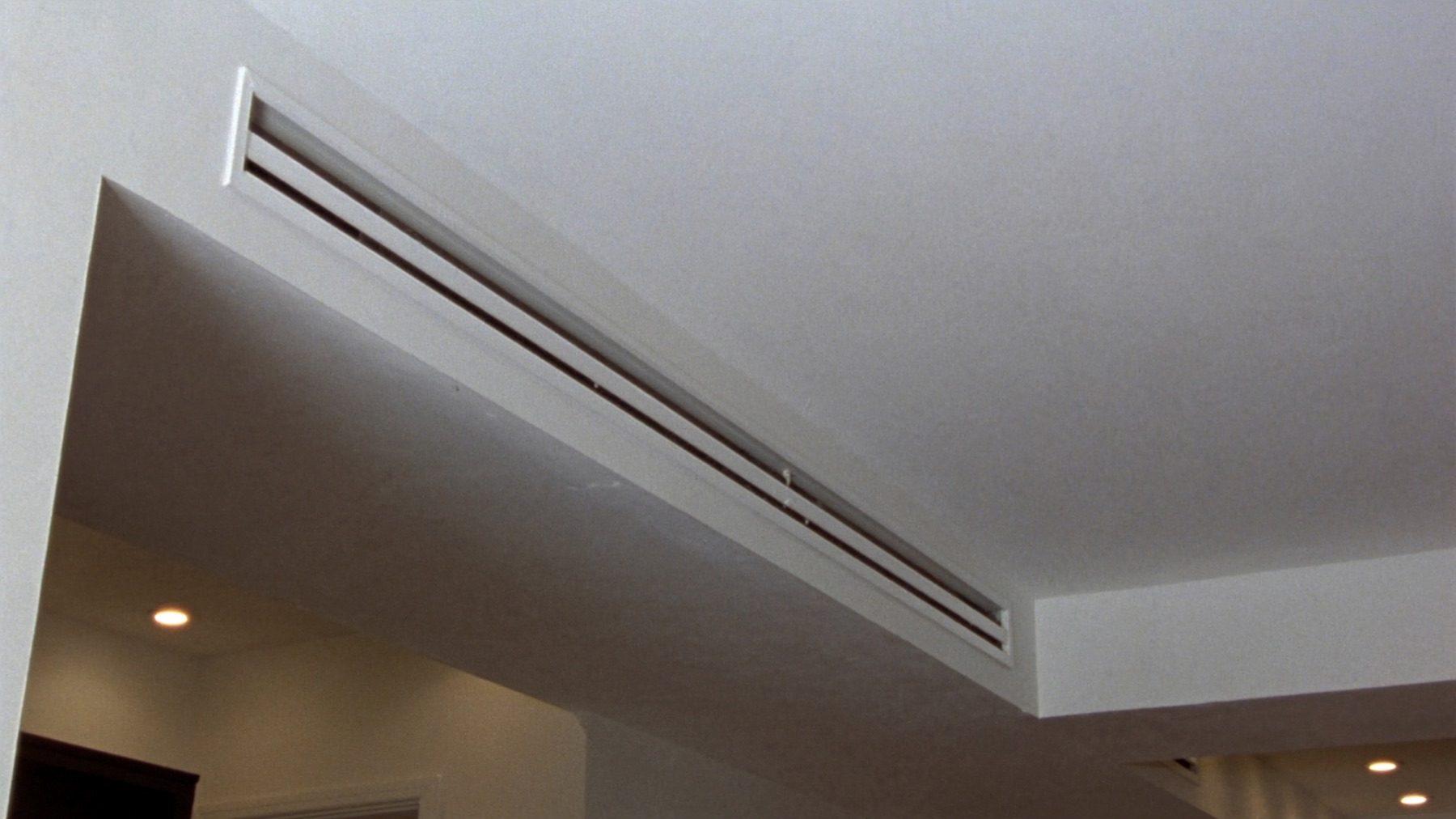 Slim linear ducted air conditioning outlet in a living room ceiling