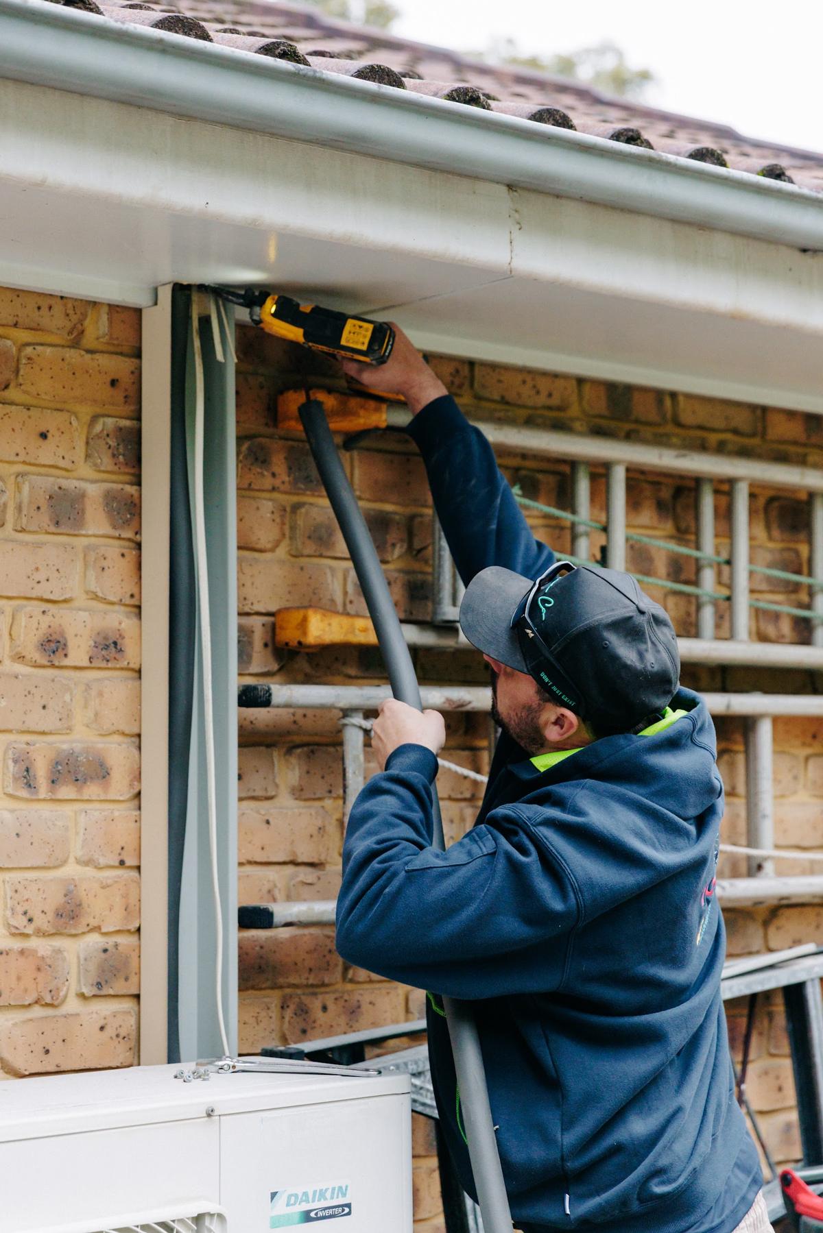 Technician drilling and sealing a wall penetration