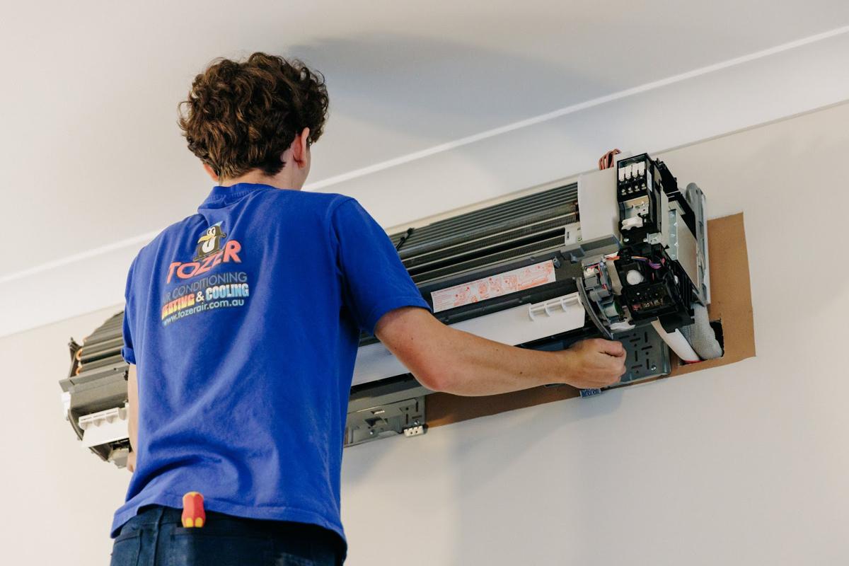 Technician fitting a wall-mounted split system head unit