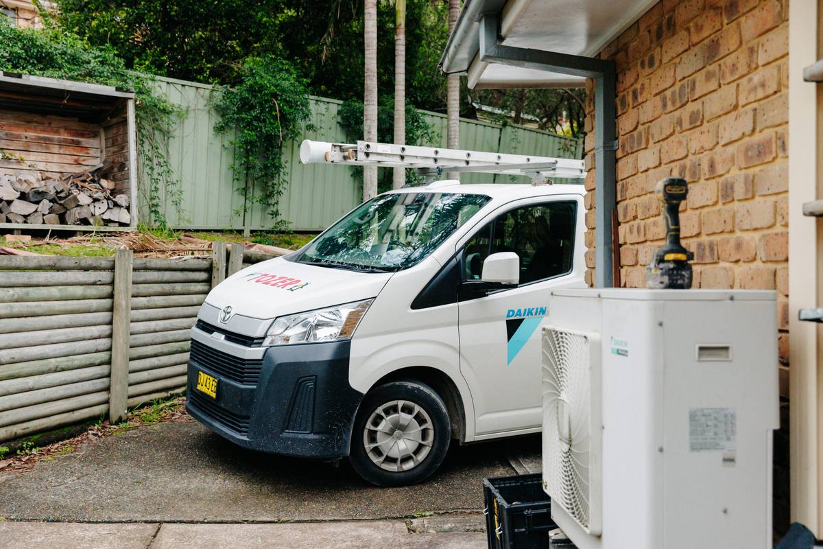 A TOZER van in a home’s driveway beside a Daikin outdoor unit
